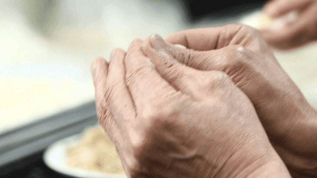 Wrinkled hands of old man making dumplings