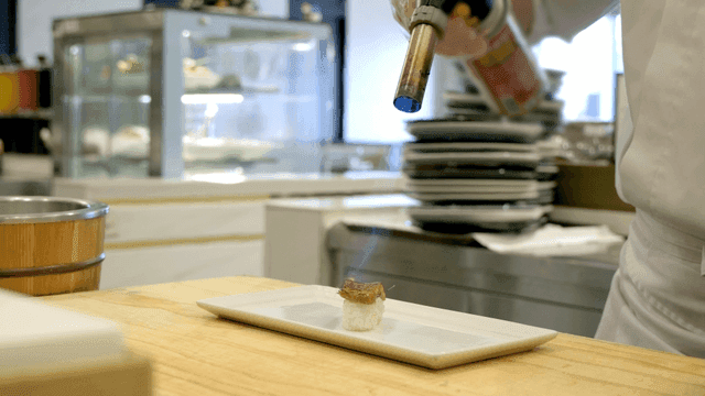 Chef using torch on eel sushi in kitchen