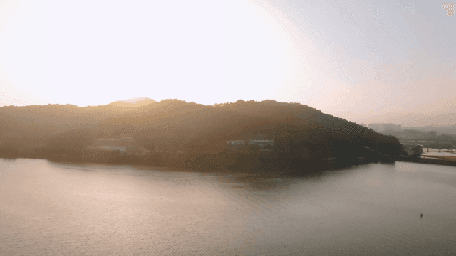 Tranquil lake where sun rises over hill