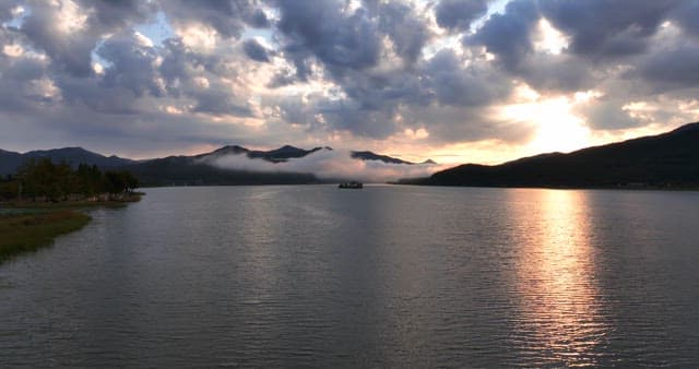 일몰에 산이 있는 고요한 강