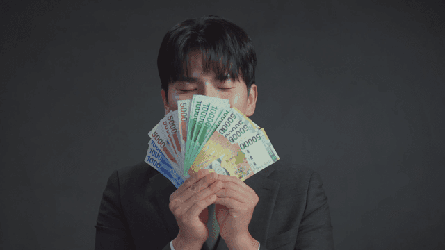 만족스러운 표정으로 돈 냄새를 맡는 남자