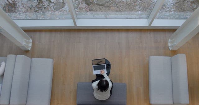 Person Working on Laptop in front of Big Windows