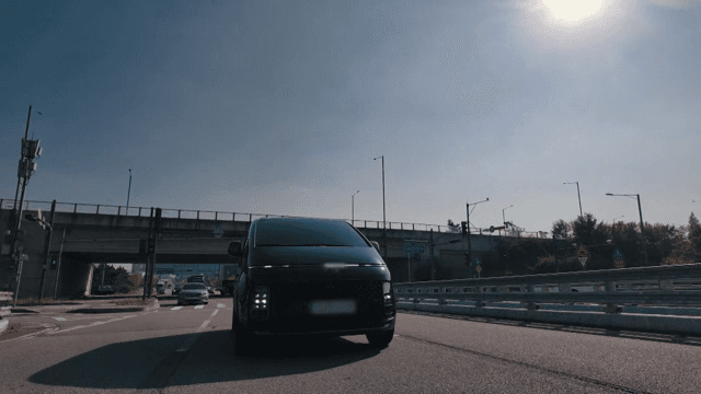 Black van driving under an overpass