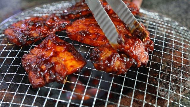 타오르는 숯불 위 그릴에서 지글지글 구워지는 고기