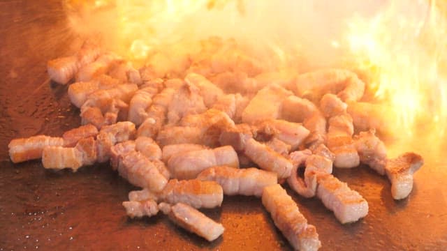 불타는 철판에서 육즙이 가득한 삼겹살 굽기