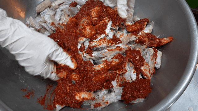 Mixing fish with spicy seasoning in a bowl