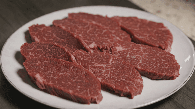 Fresh raw beef slices on a white plate