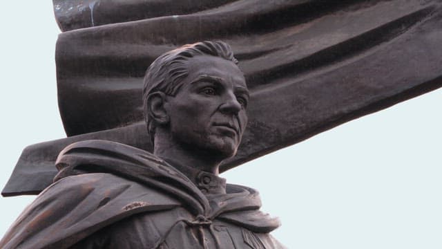 흐린 하늘 아래 망토를 두른 남자의 역사적 동상