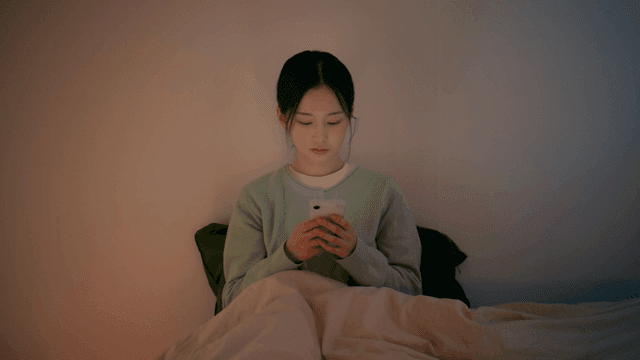 Young woman using smartphone in bed