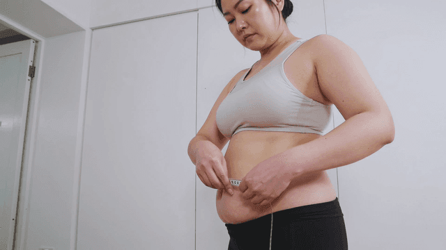 Obese women measuring their waistlines