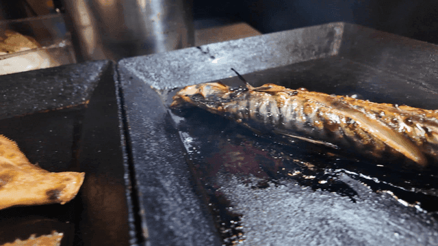 Grilled fish sizzling on a hot pan