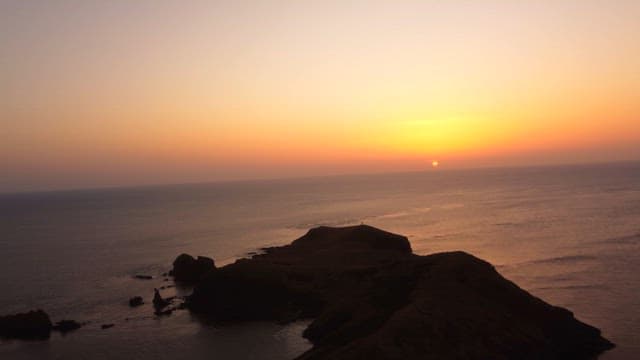 바위 절벽과 고요한 바다 위의 일몰