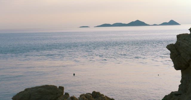 Peaceful Rocky Coast at Dusk with Islands in the Distance