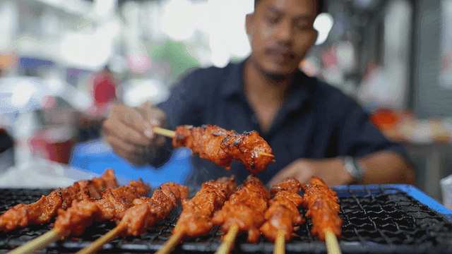 Man grilling muping skewers at street stall