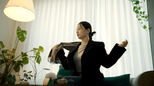 Woman sitting on sofa at home and unbuttoning her scarf