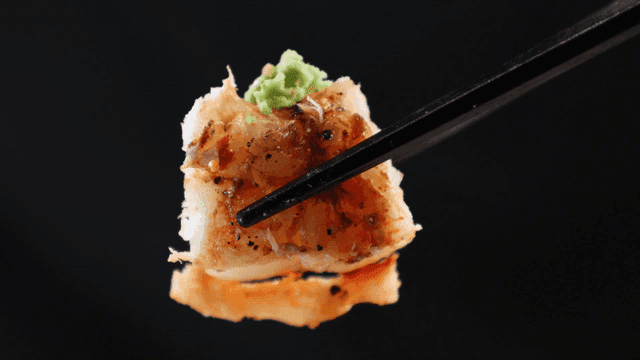 Grilled shrimp topped with wasabi picked up with chopsticks