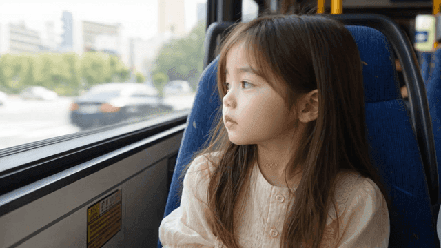 Young girl looking out bus window