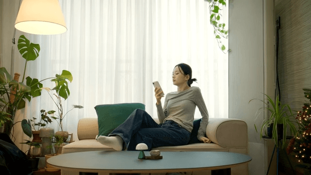 Woman lying on sofa looking at her phone after returning home