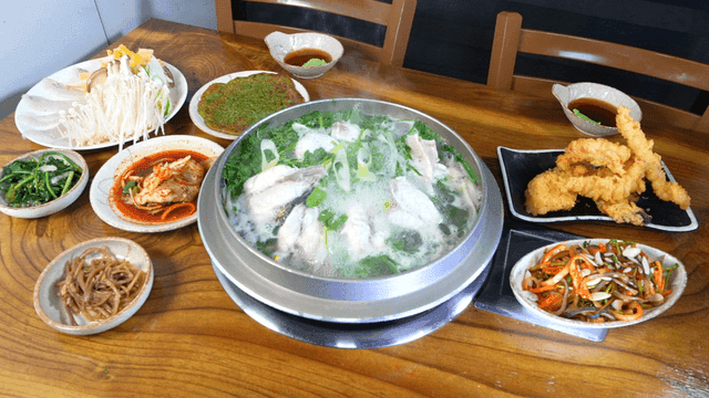 Table set with Korean food, including pufferfish clear soup.