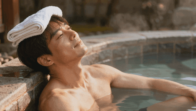 수건을 얹고 온천에서 휴식을 취하는 남자