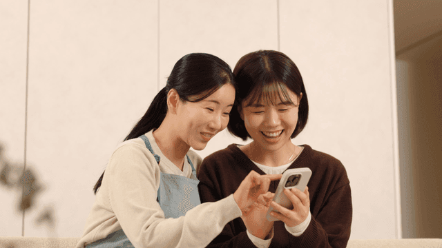 Mother and daughter laughing while looking at their cell phones