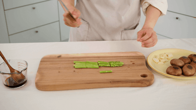 Chef chopping asparagus on cutting board