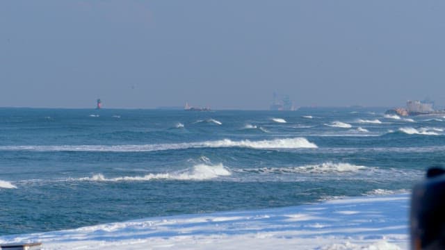 Raging waves crashing onto a snow-covered beach