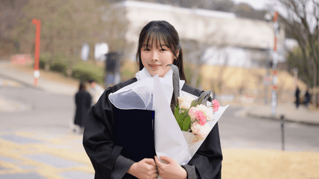Graduate holding flowers and diploma