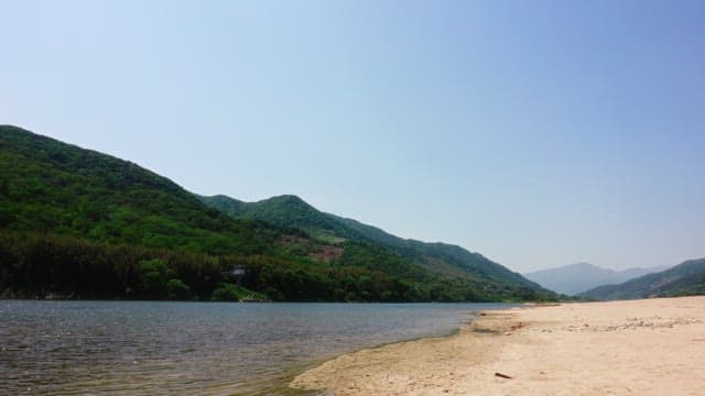 Serene riverside and green mountain landscape on a clear day