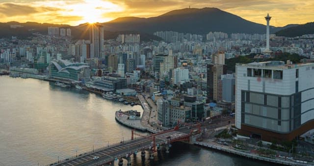 From evening to night view of a bustling port city with tall skyscrapers and bridge