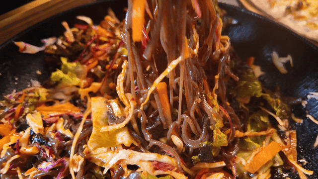 Chopsticks lifting bibim makguksu noodles and bossam