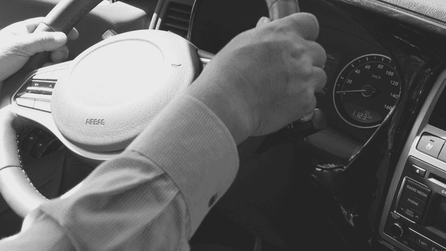 A hand gripping a car steering wheel