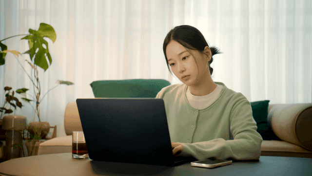 Tired woman working on laptop in living room