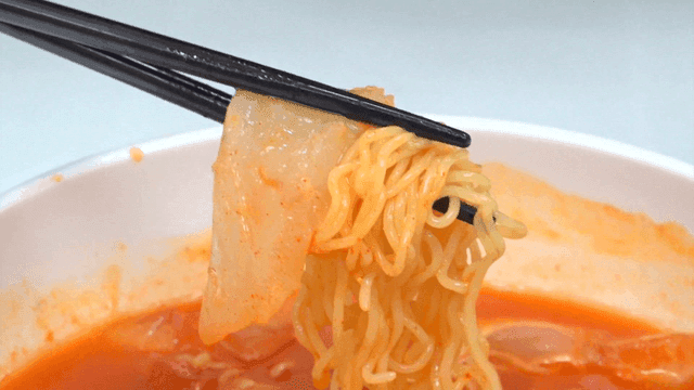 Chopsticks lifting mulhoe bibim ramen with sashimi