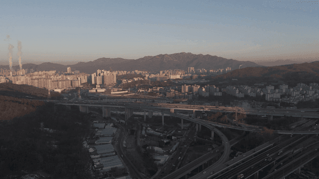 산을 배경으로 한 넓은 고속도로들이 연결된 도시