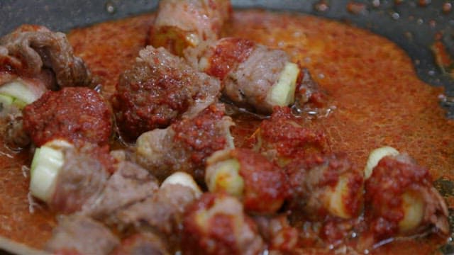 팬에서 요리 중인 대파 소고기 말이