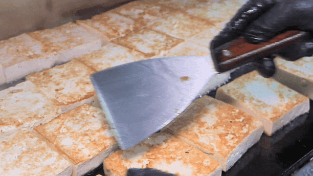 Tofu being grilled on a hot pan