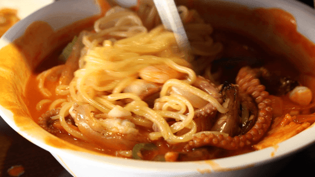 Chopsticks stirring spicy seafood jjamppong in bowl