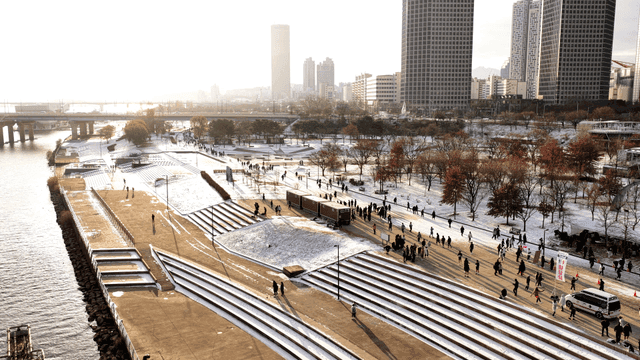 Snow-covered riverside park where people are walking