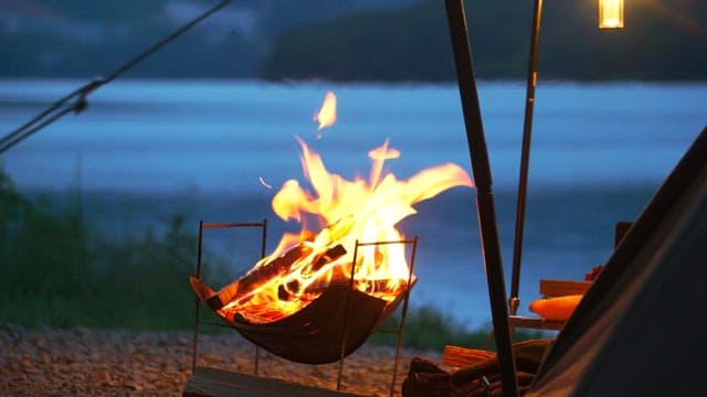 Campfire burning in the brazier brightly by a lakeside in the evening