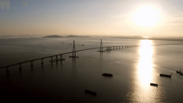 일몰 시 고요한 바다 위의 긴 다리