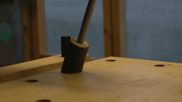 철 막대와 연결된 나무 토막을 살펴보는 손