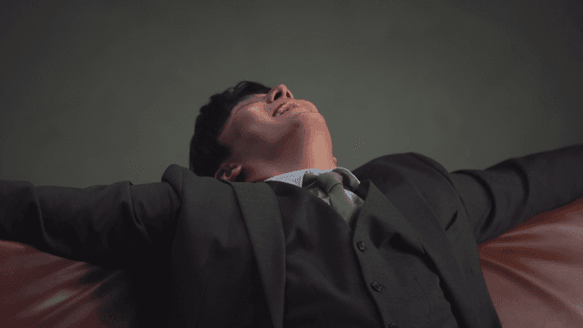 Cash raining down on a man sitting on a sofa