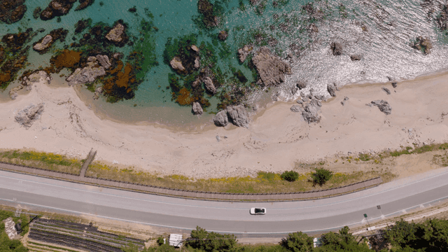 A coastal road alongside a rocky beach