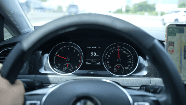 Hands gripping steering wheel while driving on highway