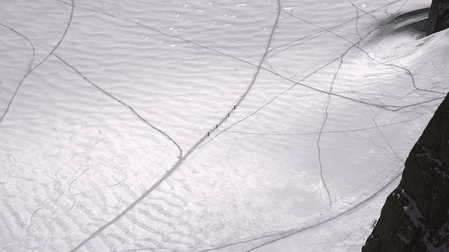 Hikers crossing a snowy mountain landscape