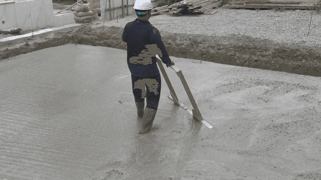 Worker leveling wet concrete at a site