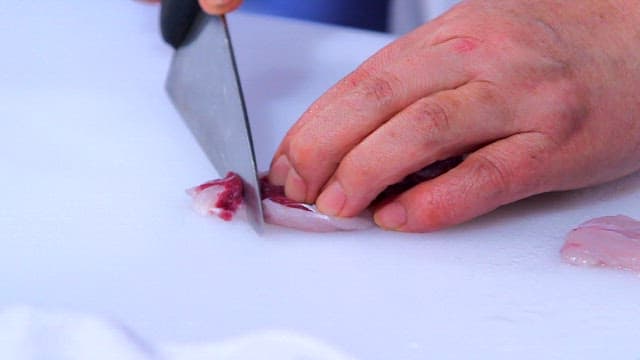 Slicing fresh gray mullet on a cutting board