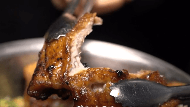 Seasoned eel being torn apart with tongs