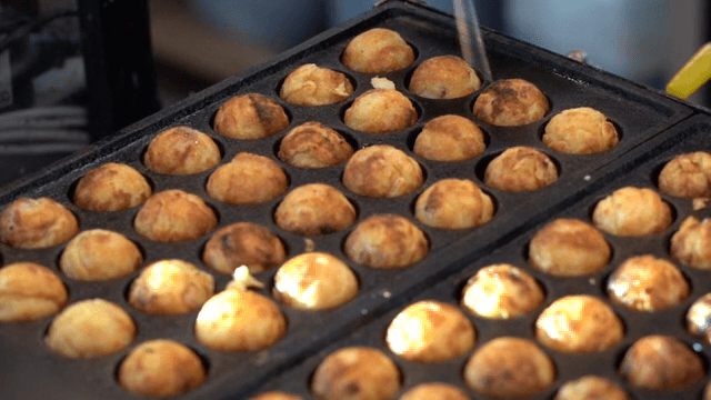 Takoyaki being cooked on a hot griddle